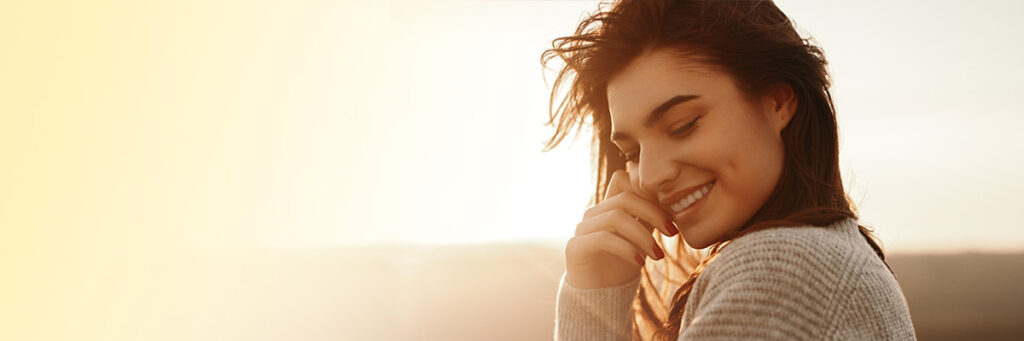Woman outside in a sweater smiling at dusk